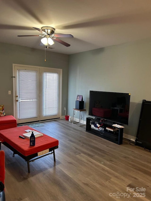 living area featuring baseboards, wood finished floors, and a ceiling fan