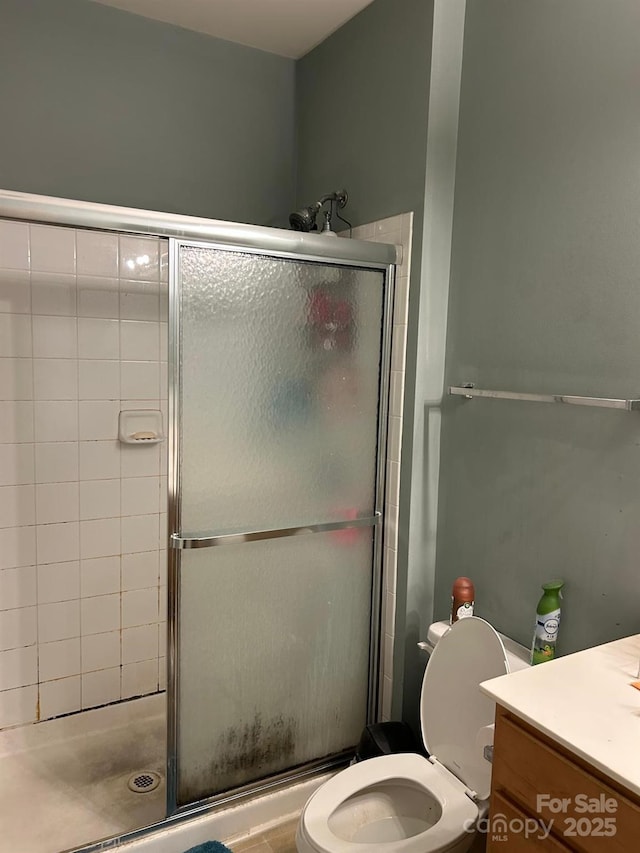 full bathroom featuring toilet, a stall shower, and vanity