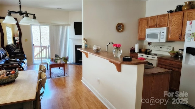 93 Foxden Dr Unit 101, Fletcher, NC 28732 - kitchen with white appliances, light wood-style floors, a kitchen breakfast bar, brown cabinets, and a peninsula