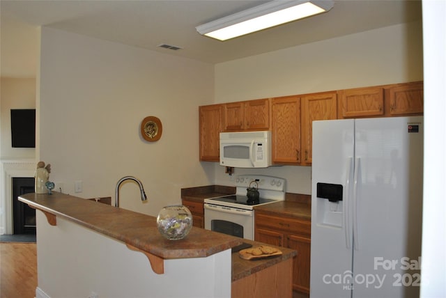 93 Foxden Dr Unit 101, Fletcher, NC 28732 - kitchen featuring white appliances, a breakfast bar area, brown cabinetry, dark countertops, and a peninsula