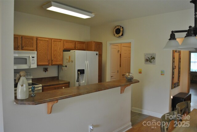 93 Foxden Dr Unit 101, Fletcher, NC 28732 - kitchen featuring white appliances, dark countertops, a kitchen breakfast bar, and brown cabinets