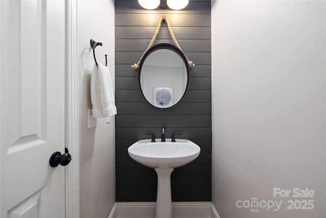 bathroom featuring wooden walls and a sink