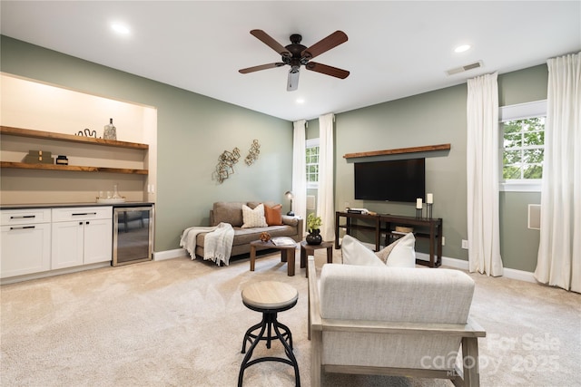 living area with beverage cooler, indoor wet bar, light carpet, visible vents, and a ceiling fan