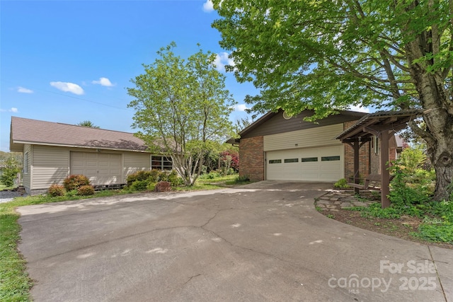 view of home's exterior with brick siding, driveway, a garage, and an outbuilding