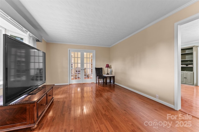 unfurnished room with crown molding, wood finished floors, french doors, and baseboards