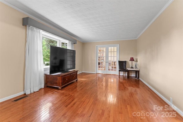 living room featuring french doors, baseboards, ornamental molding, visible vents, and light wood-style floors