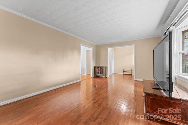 unfurnished living room featuring radiator, crown molding, baseboards, and hardwood / wood-style flooring