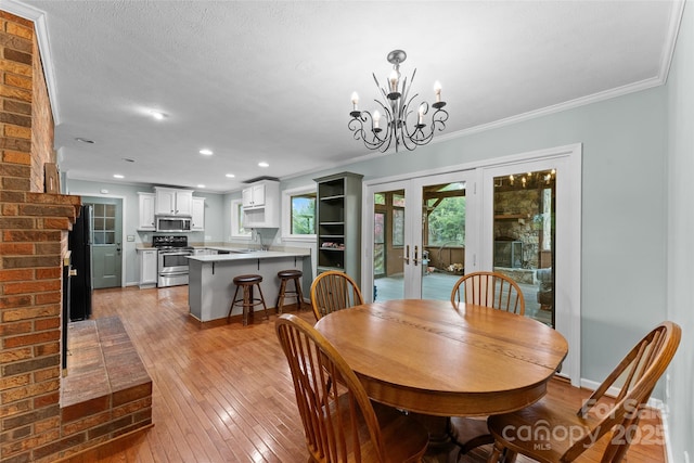 dining area featuring an inviting chandelier, light wood-style flooring, french doors, and ornamental molding