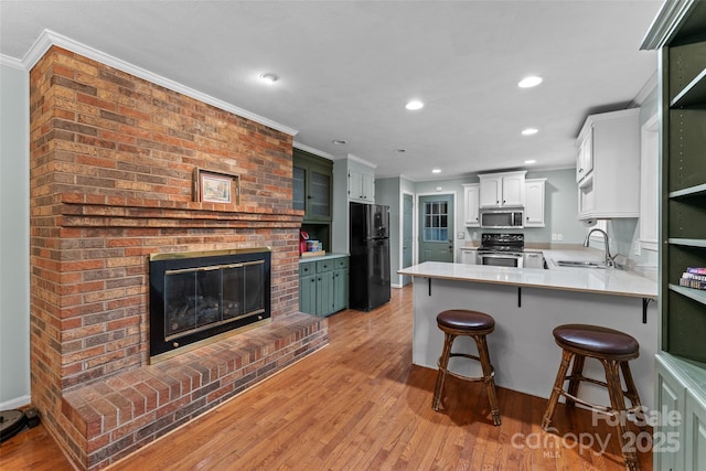kitchen featuring a peninsula, appliances with stainless steel finishes, a fireplace, and ornamental molding