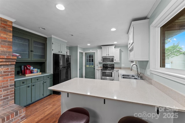 kitchen featuring a sink, a peninsula, stainless steel appliances, a breakfast bar, and crown molding