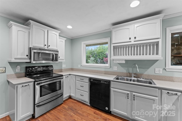 kitchen with crown molding, appliances with stainless steel finishes, white cabinetry, and a sink