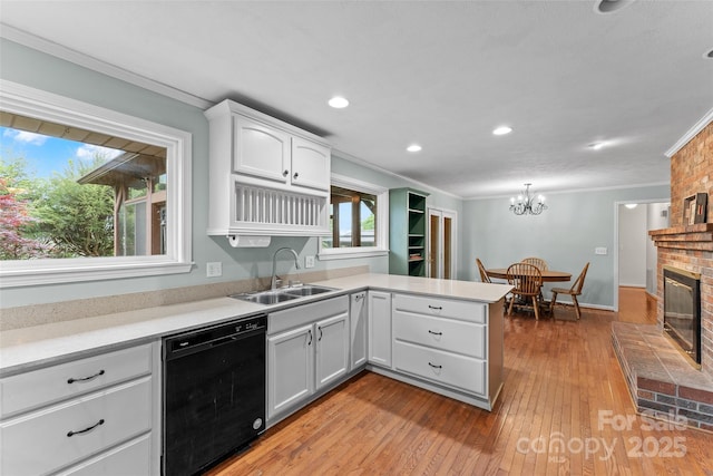 kitchen with a peninsula, a sink, black dishwasher, crown molding, and white cabinetry