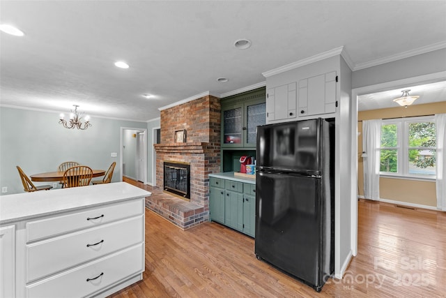 kitchen with freestanding refrigerator, crown molding, light countertops, and light wood-style floors