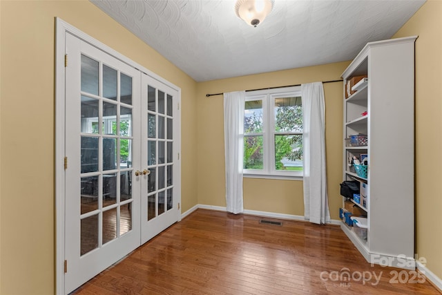 doorway with hardwood / wood-style flooring, baseboards, french doors, and visible vents