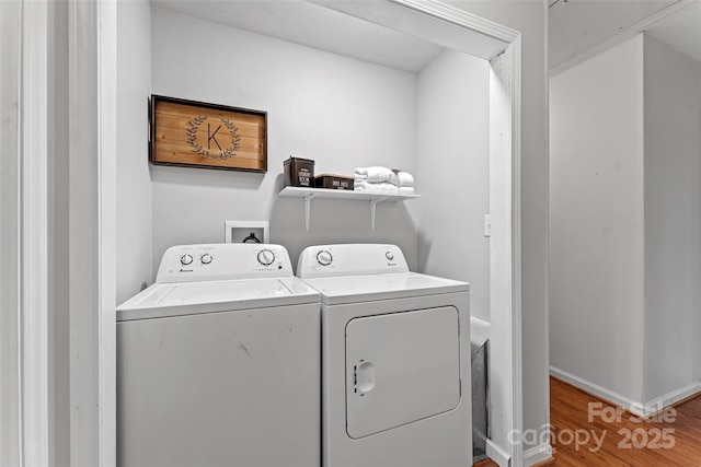 washroom with laundry area, washer and clothes dryer, wood finished floors, and baseboards