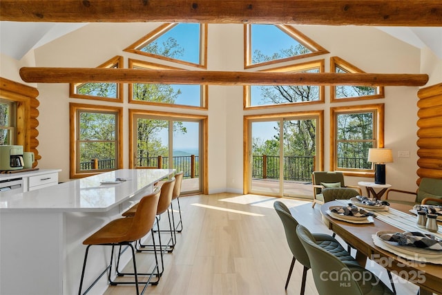 kitchen with light wood-style floors, a kitchen breakfast bar, high vaulted ceiling, a center island, and white cabinetry