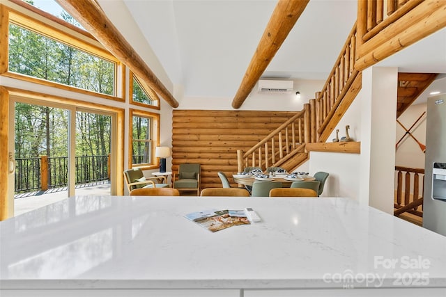 kitchen with rustic walls, beamed ceiling, a wall mounted air conditioner, a high ceiling, and light stone counters