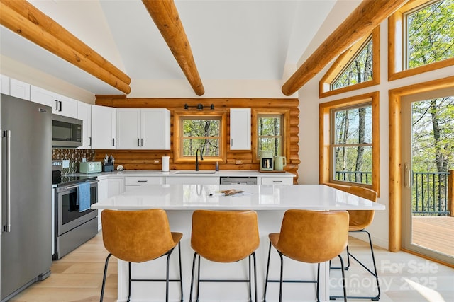 kitchen with a breakfast bar area, stainless steel appliances, a sink, and light countertops