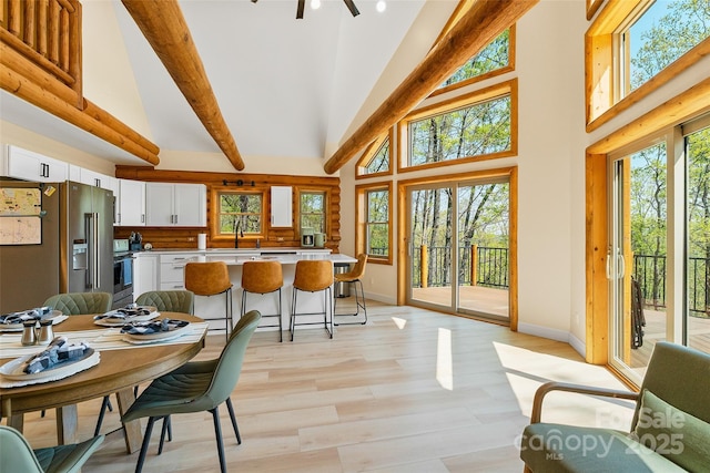 dining room featuring baseboards, a healthy amount of sunlight, and high vaulted ceiling