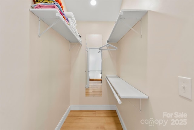 walk in closet with wood finished floors