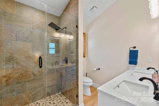full bath with toilet, visible vents, a shower stall, and a sink