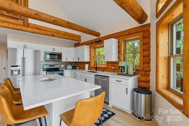 153 Chetan Way, Lake Lure, NC 28746 - kitchen with rustic walls, a breakfast bar area, light countertops, a sink, and stainless steel appliances