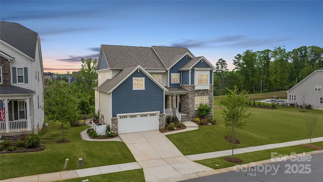 craftsman-style home featuring a front yard, an attached garage, driveway, and stone siding