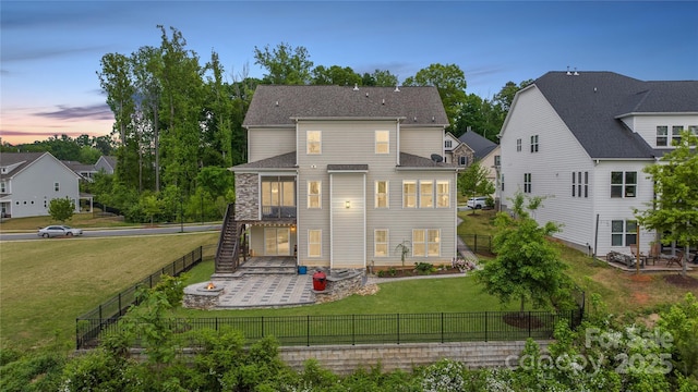 back of house at dusk featuring a yard, stairway, a fenced backyard, and a patio area