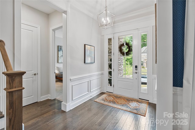 foyer entrance featuring a decorative wall, a notable chandelier, wainscoting, and dark wood-type flooring