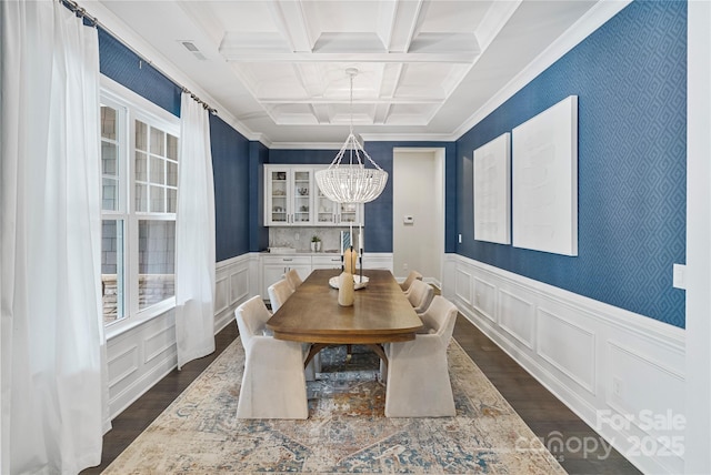 dining space featuring dark wood finished floors, a chandelier, coffered ceiling, and beamed ceiling