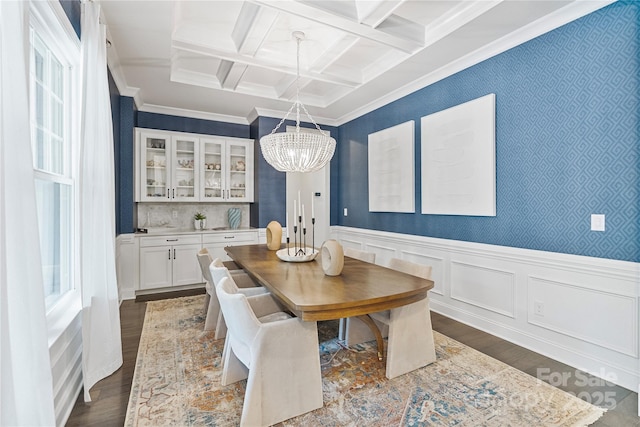 dining area featuring ornamental molding, wainscoting, dark wood-type flooring, a chandelier, and coffered ceiling