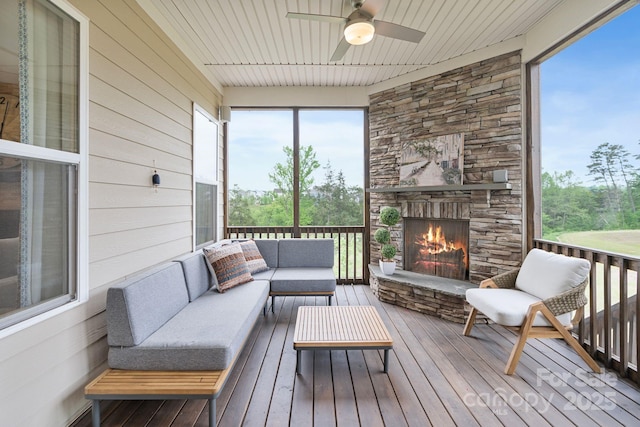 sunroom featuring a ceiling fan, an outdoor living space with a fireplace, and a wealth of natural light