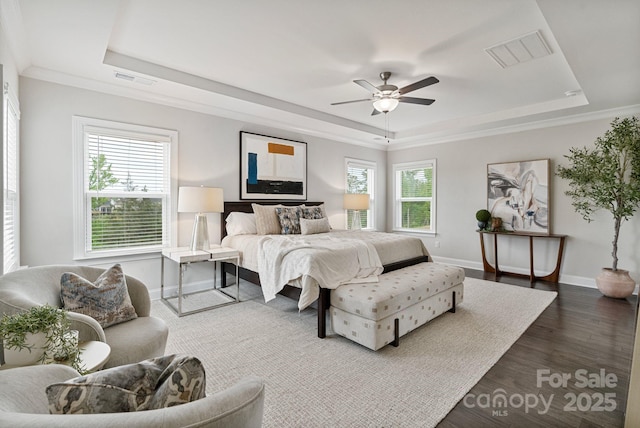 bedroom with a ceiling fan, baseboards, a tray ceiling, visible vents, and dark wood-style floors