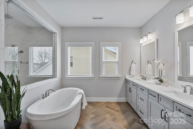 bathroom featuring tiled shower, a freestanding tub, visible vents, and a sink