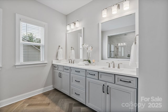 full bath featuring a sink, baseboards, a shower, and double vanity