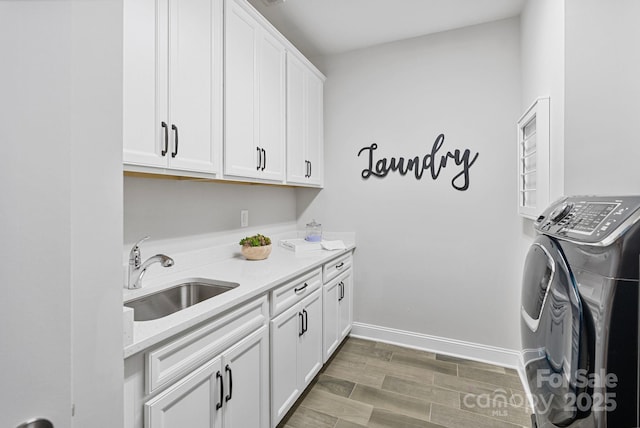 laundry room with cabinet space, separate washer and dryer, baseboards, and a sink