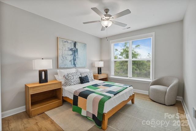 bedroom with baseboards, a ceiling fan, wood finished floors, and visible vents