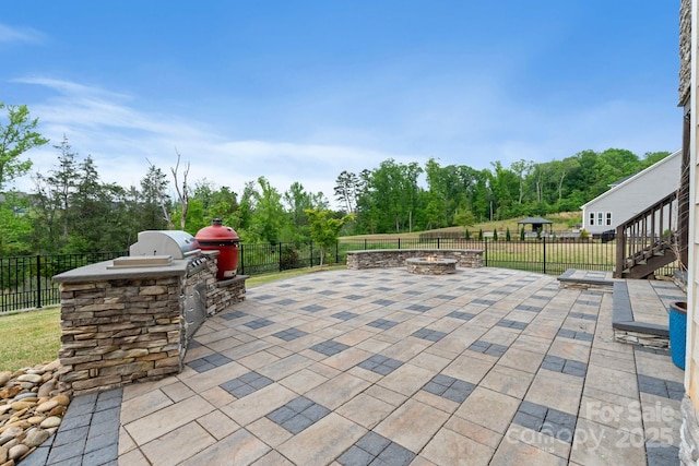 view of patio / terrace with an outdoor kitchen, a fenced backyard, and an outdoor fire pit