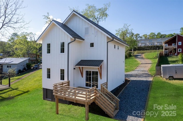 back of house featuring a deck, a standing seam roof, board and batten siding, metal roof, and a yard