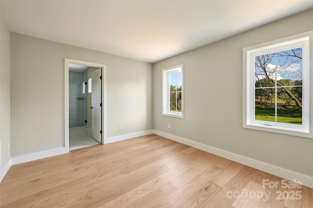 unfurnished bedroom with light wood-type flooring, connected bathroom, and baseboards