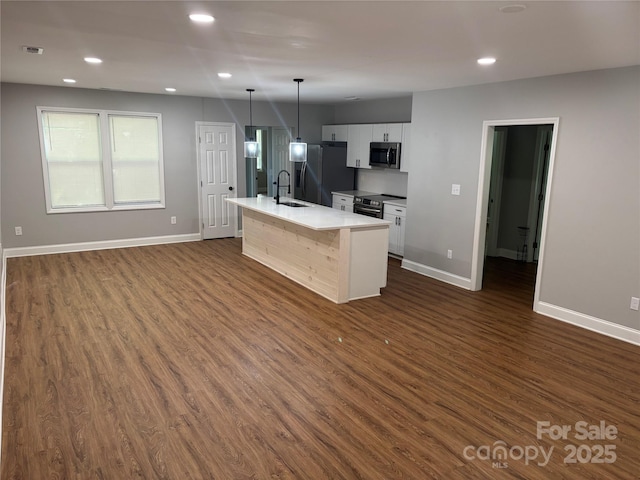 kitchen with baseboards, stainless steel appliances, dark wood-style flooring, a sink, and white cabinetry