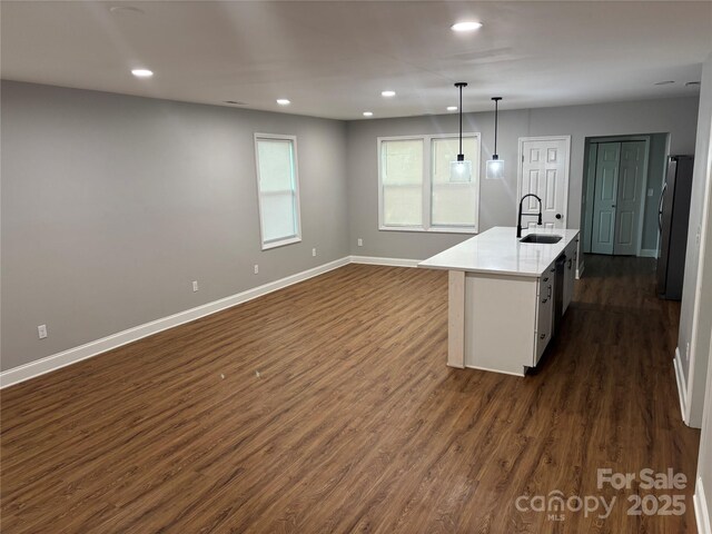 kitchen featuring recessed lighting, a sink, dark wood-style flooring, baseboards, and freestanding refrigerator