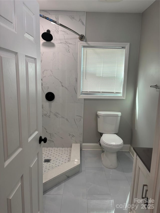bathroom featuring baseboards, a marble finish shower, toilet, vanity, and marble finish floor