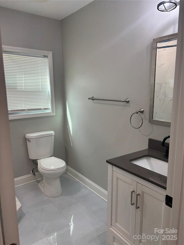 bathroom with baseboards, marble finish floor, toilet, and vanity