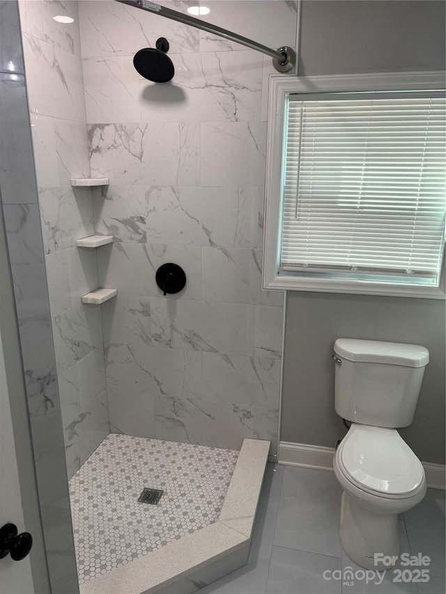 bathroom featuring baseboards, tiled shower, and toilet