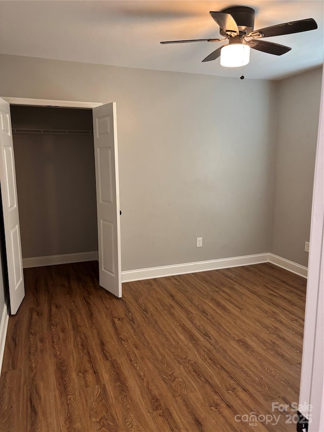 unfurnished bedroom featuring baseboards, ceiling fan, a closet, and dark wood-type flooring