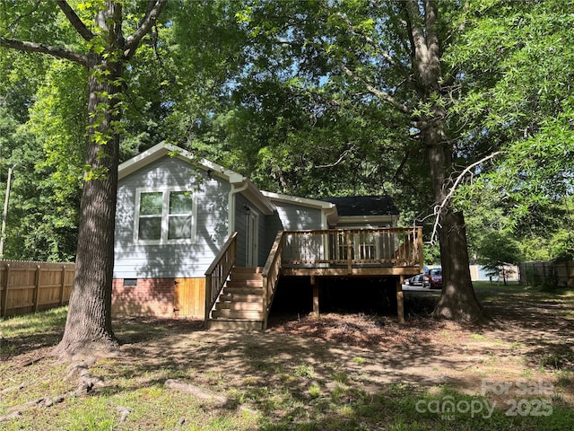 back of property with a wooden deck, crawl space, stairway, and fence