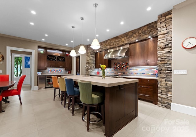 2915 Cutter Ct, Waxhaw, NC 28173 - kitchen with wall chimney range hood, decorative backsplash, a large island, light countertops, and recessed lighting
