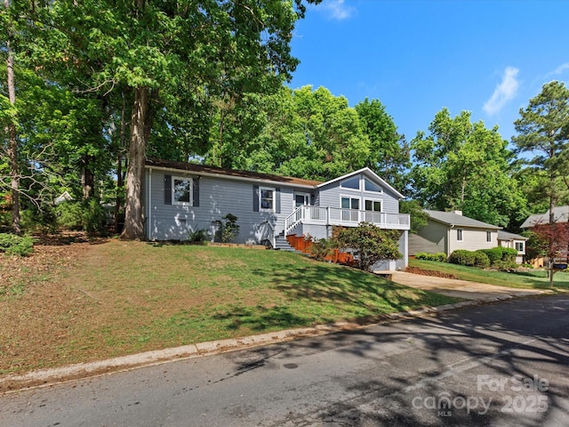 view of front of home featuring a deck, concrete driveway, and a front yard