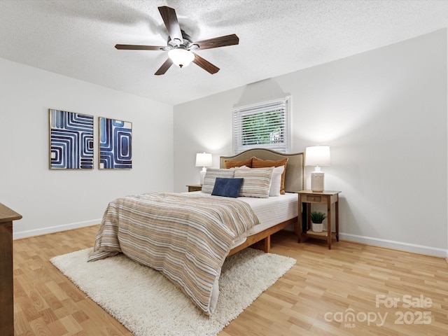 bedroom with baseboards, wood finished floors, and a textured ceiling